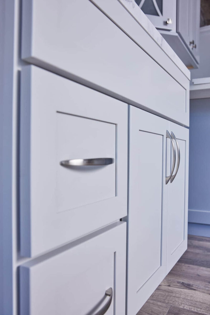 White kitchen cabinets with silver handles, close-up view.