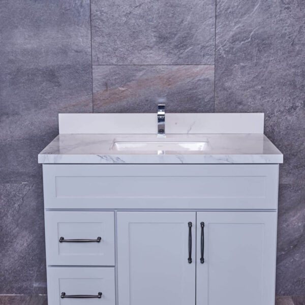 White bathroom vanity with marble countertop and gray tile background.