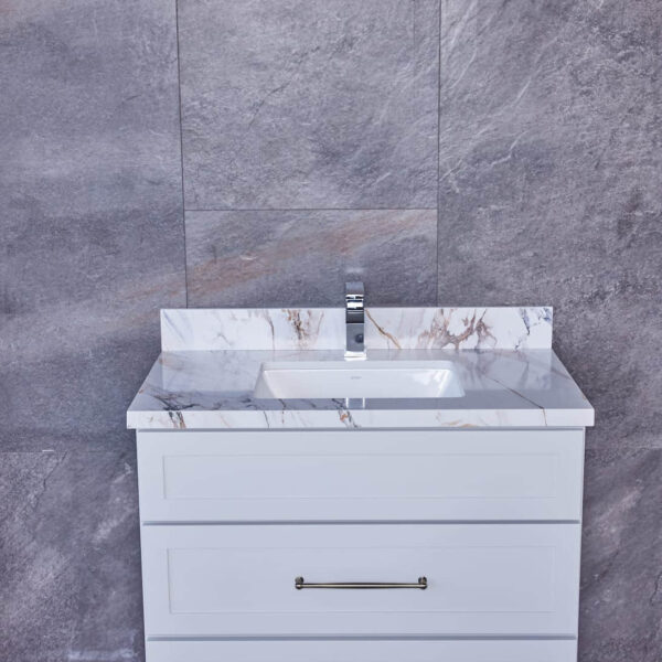 White bathroom vanity with marble countertop against gray tiled wall.