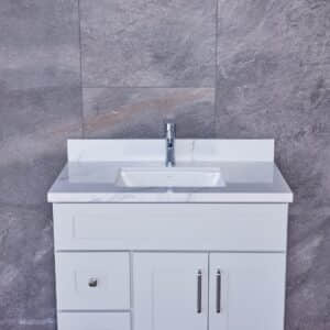 White bathroom vanity with marble countertop and modern faucet.