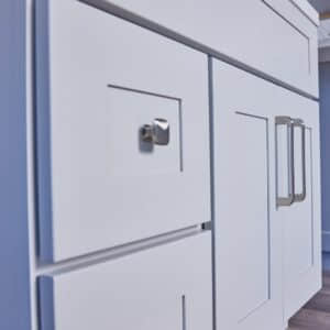 White kitchen cabinets with modern handles in a blue-themed kitchen.
