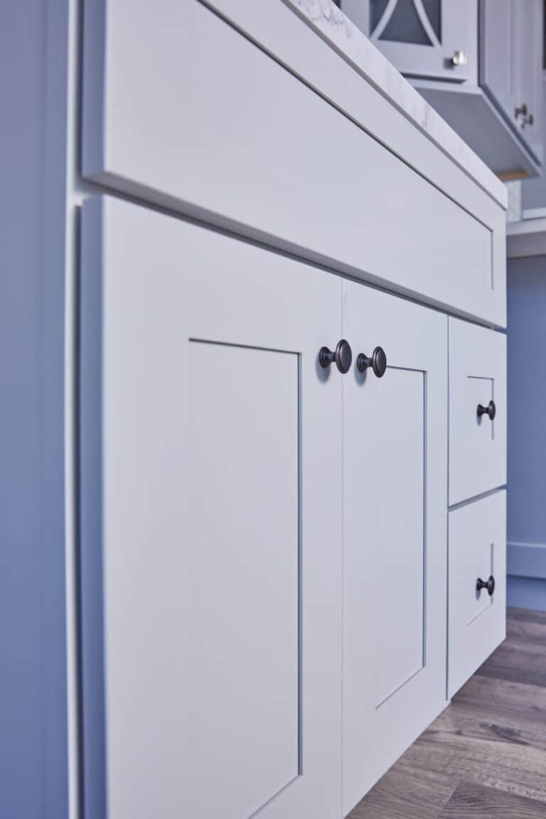 White kitchen cabinet with black knobs and drawers.