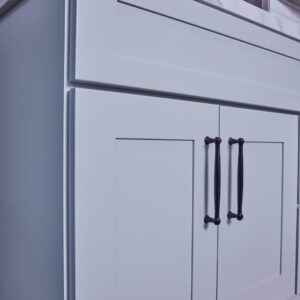 White kitchen cabinet with black handles.