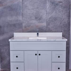 White bathroom vanity with marble countertop and gray tile background.