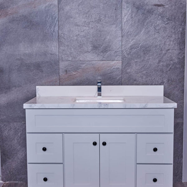 White bathroom vanity with marble countertop and gray tile background.