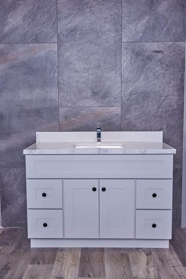 White bathroom vanity with marble countertop and gray tile background.