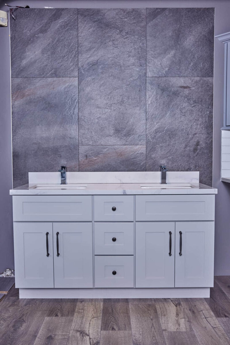 Modern bathroom vanity with dual sinks and gray stone backsplash.