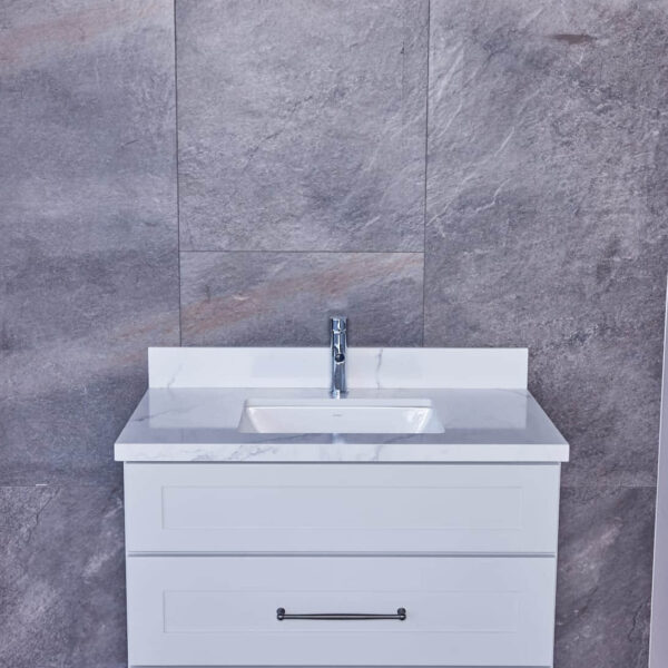 White bathroom vanity with marble countertop against gray tiled wall.