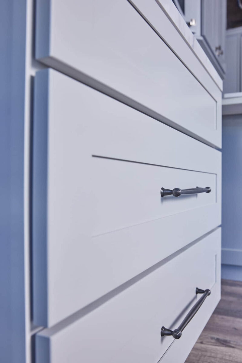 White kitchen cabinet with sleek black handle.