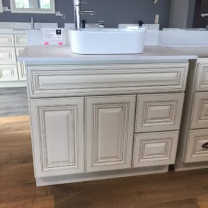 White bathroom vanity with sink on wooden floor.