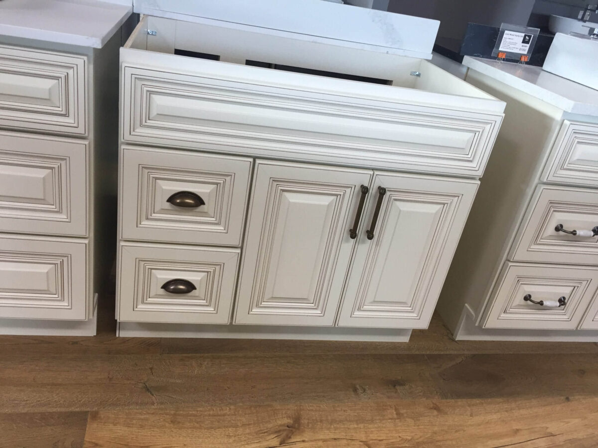 White kitchen cabinets with ornate detailing on a wooden floor.