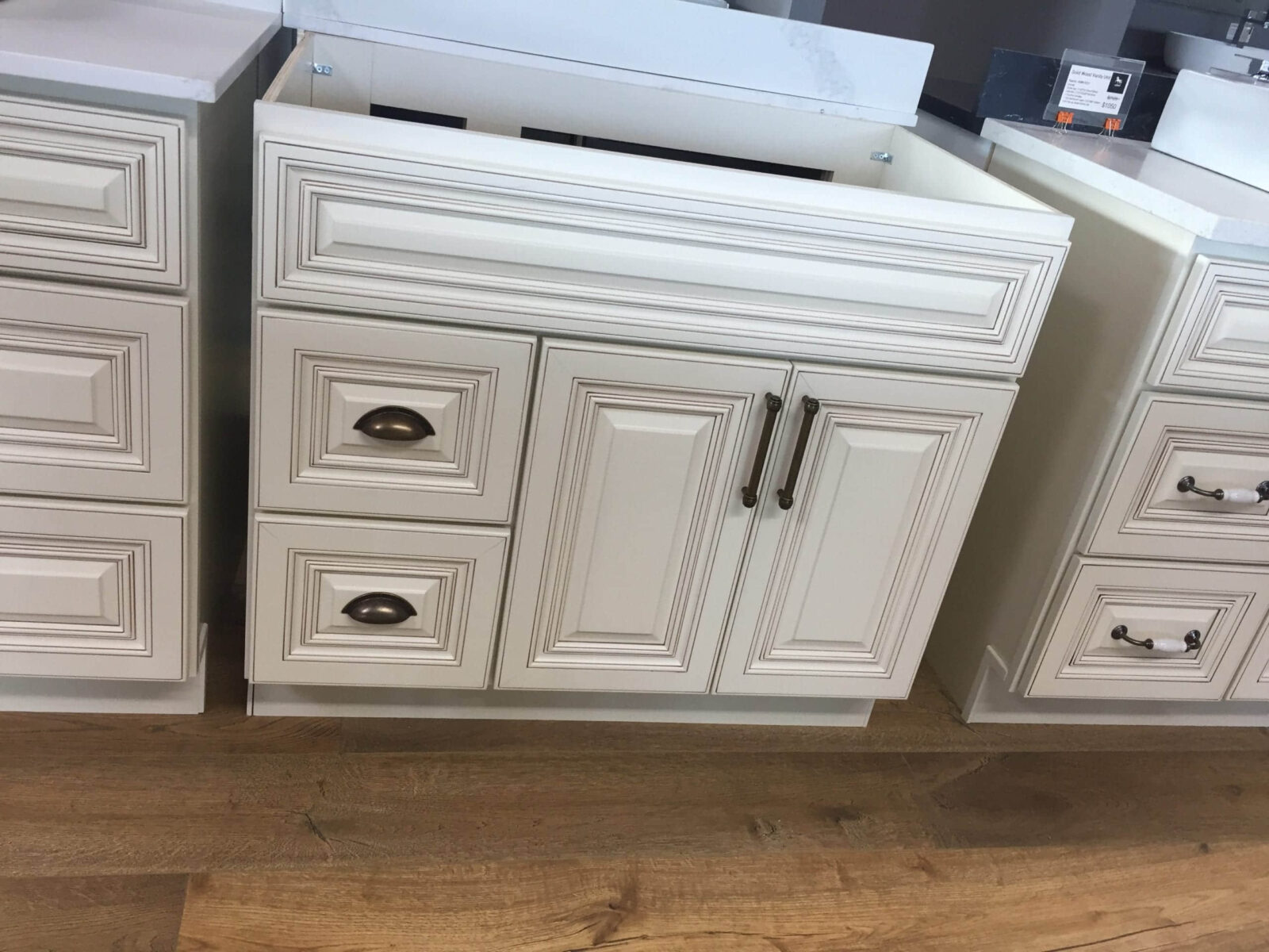 White kitchen cabinets with ornate detailing on a wooden floor.