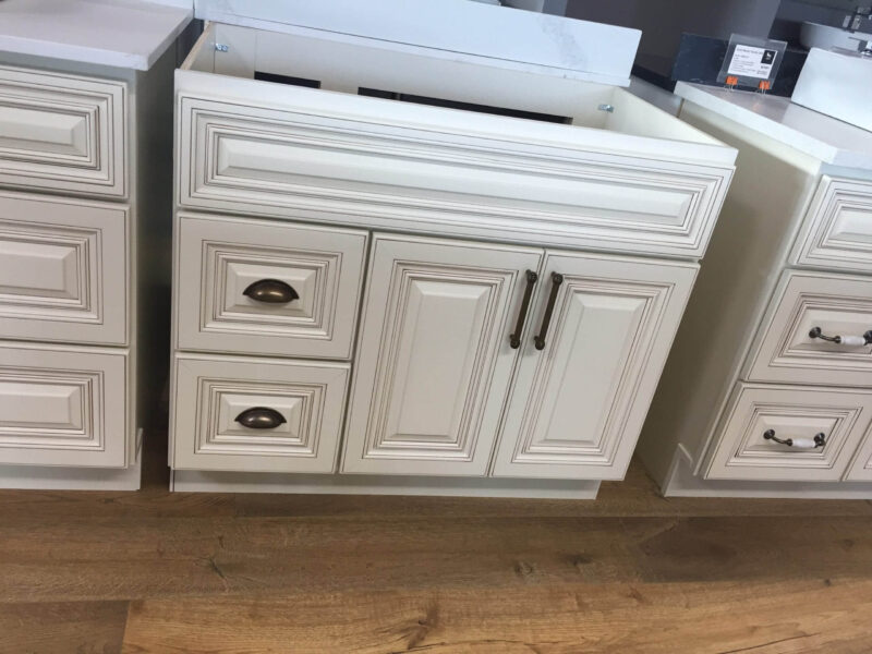 White kitchen cabinets with ornate detailing on a wooden floor.