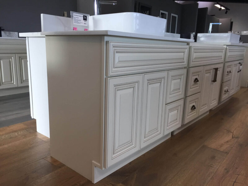 Cream kitchen cabinets with detailed paneling and a white countertop.