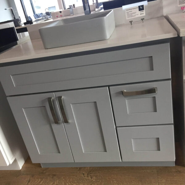 Gray kitchen cabinet with sink on display in showroom.
