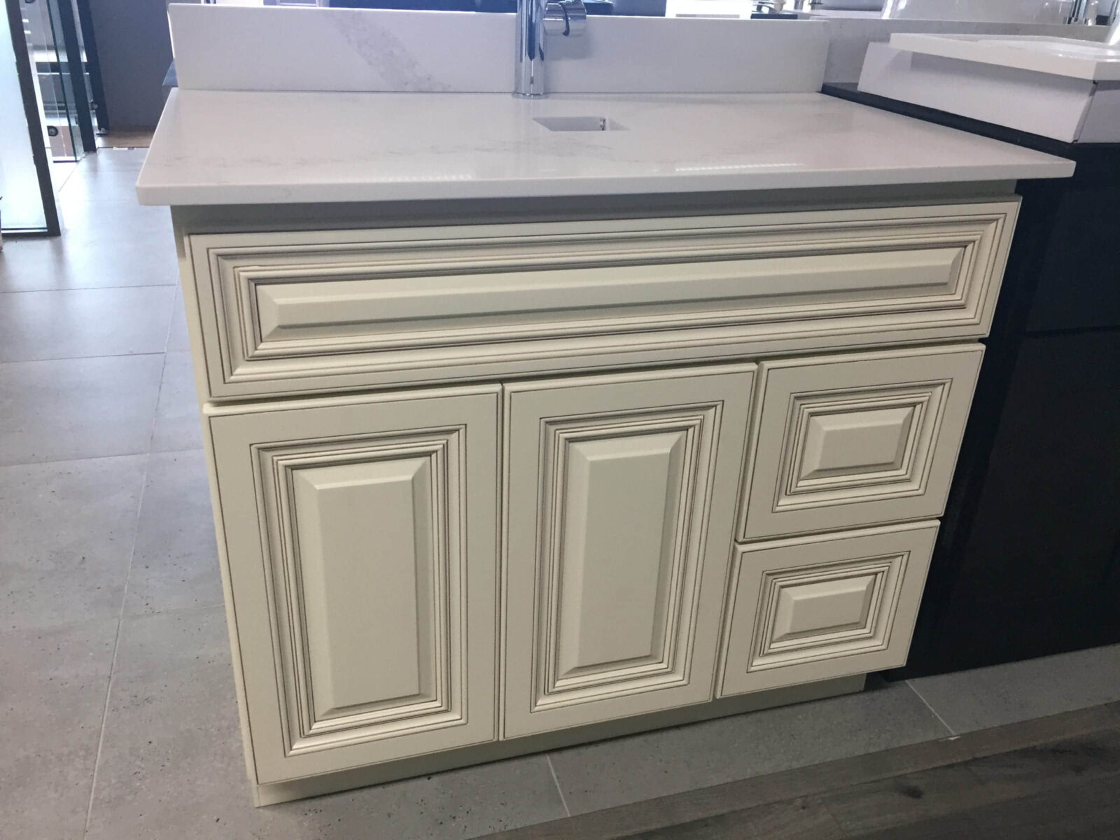 White kitchen cabinet with intricate panel design and marble countertop.