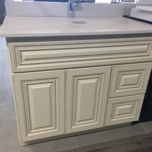 White kitchen cabinet with intricate panel design and marble countertop.