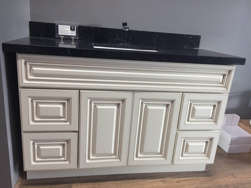 White kitchen cabinet with black countertop and sink.