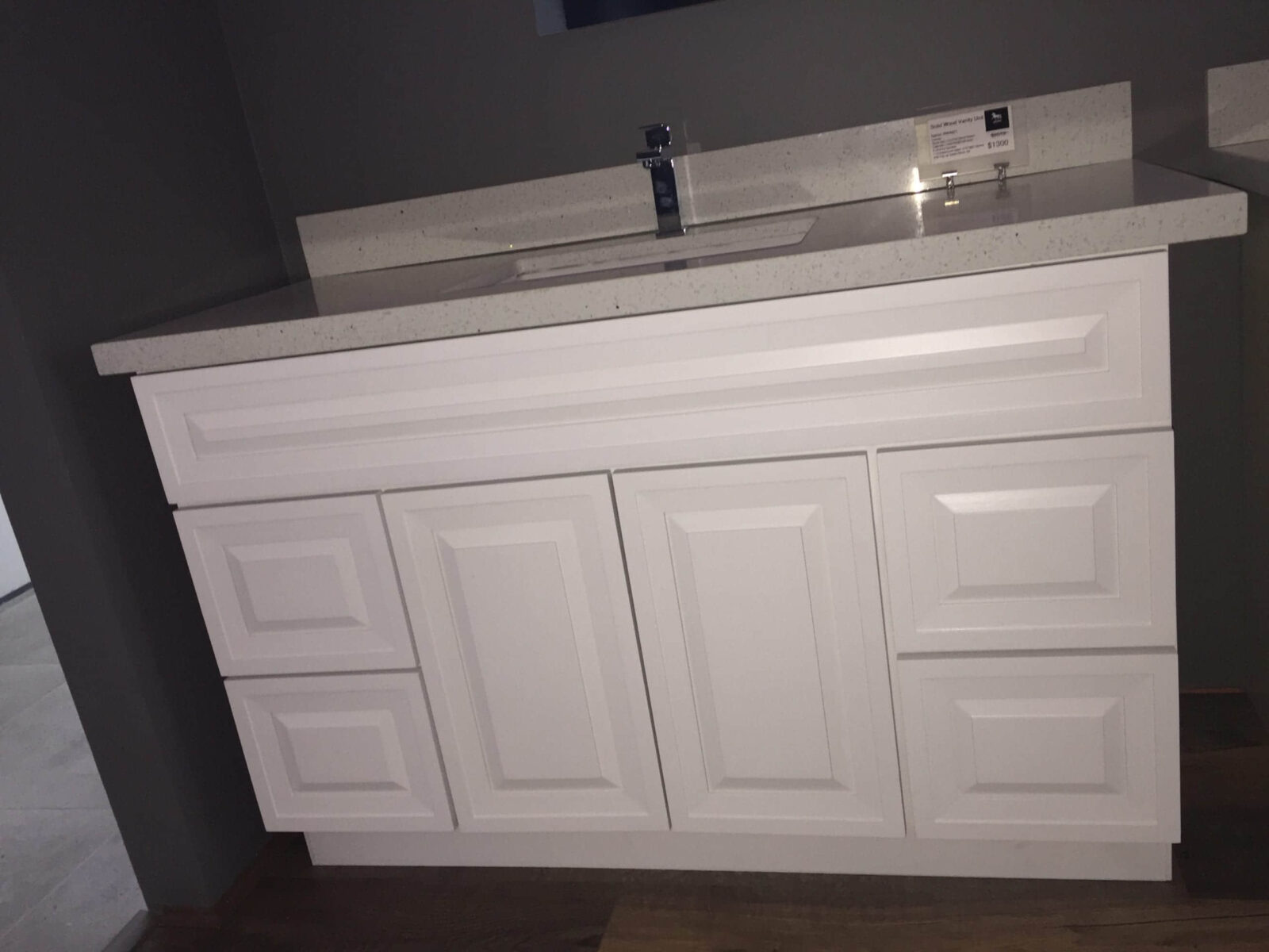 White bathroom vanity with multiple drawers and a countertop sink.