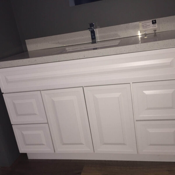 White bathroom vanity with multiple drawers and a countertop sink.