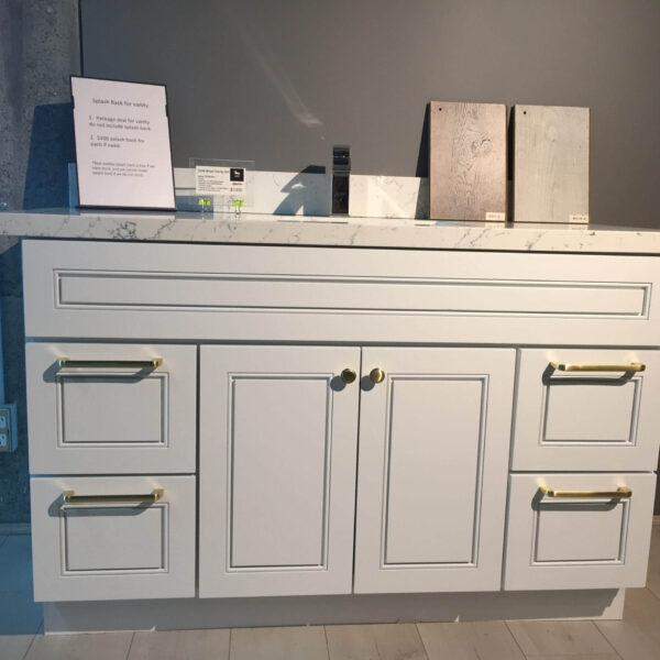 White kitchen cabinet with marble countertop and brass handles.