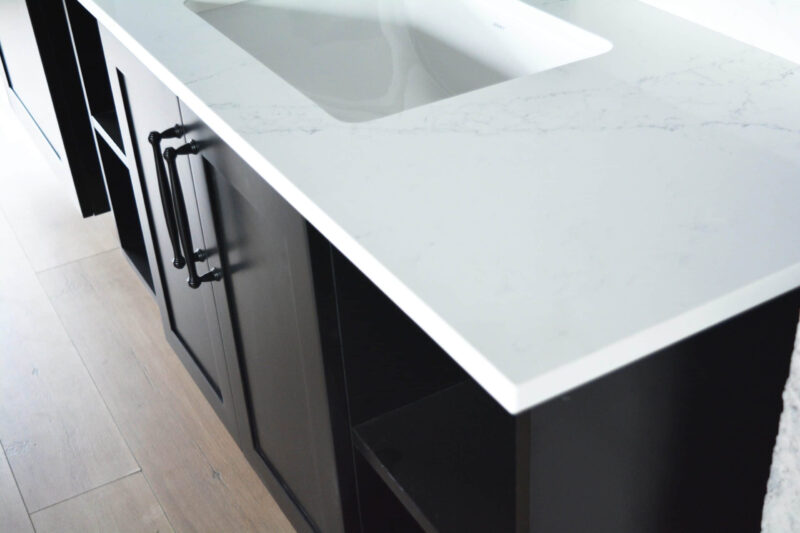 Modern kitchen countertop with white surface and dark cabinets.