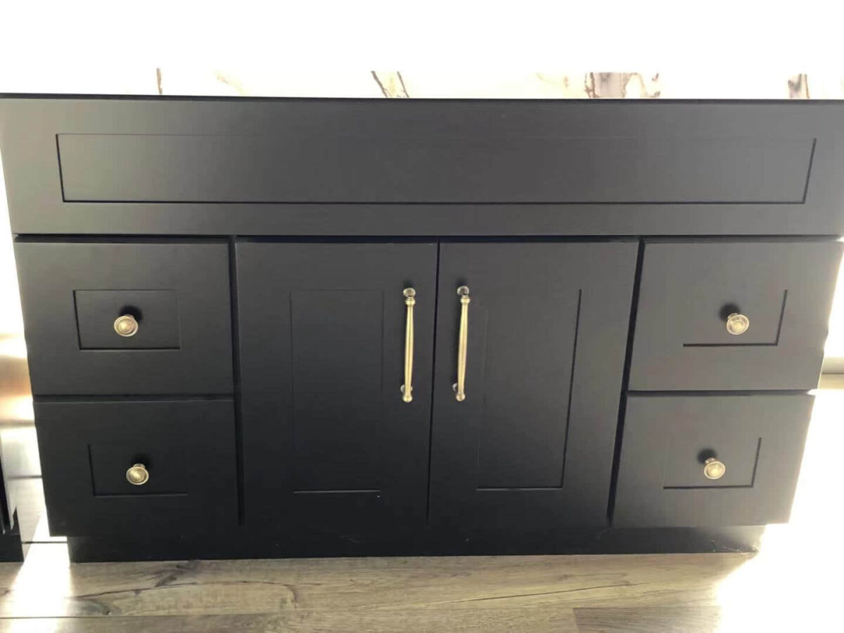 Black kitchen cabinet with silver handles on a wooden floor.