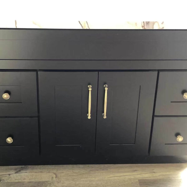 Black kitchen cabinet with silver handles on a wooden floor.
