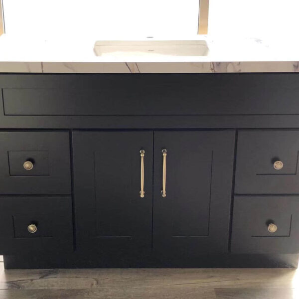 Black kitchen cabinet with marble countertop and brass handles.