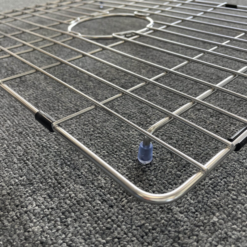 Stainless steel sink grid on textured carpet.
