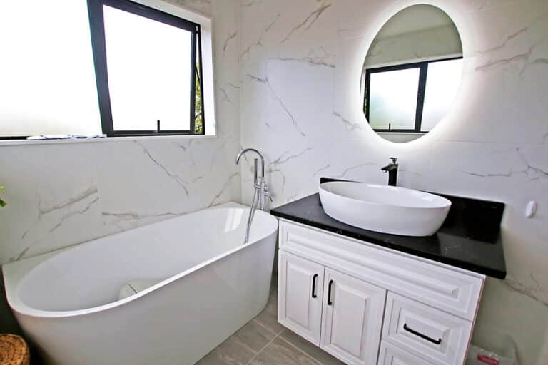 Modern bathroom with freestanding tub, vanity, and oval mirror.