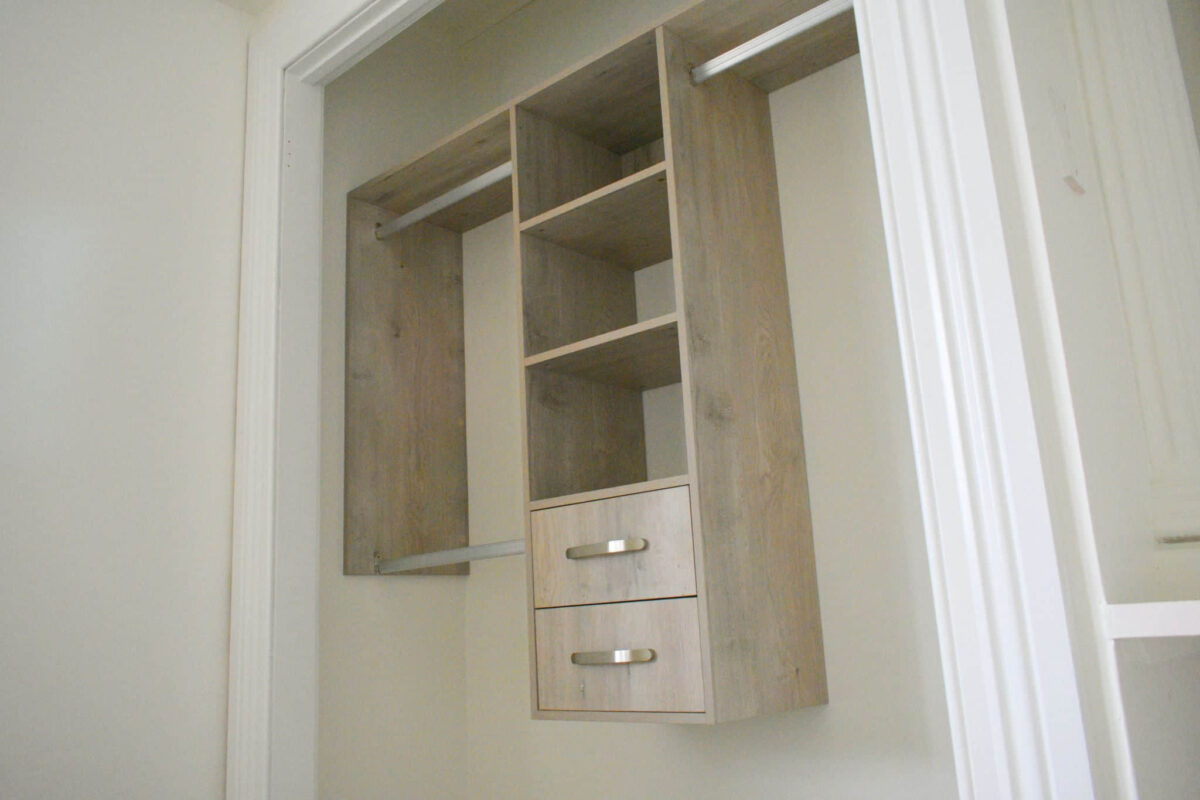 Wooden wardrobe with shelves and drawers inside a closet space.