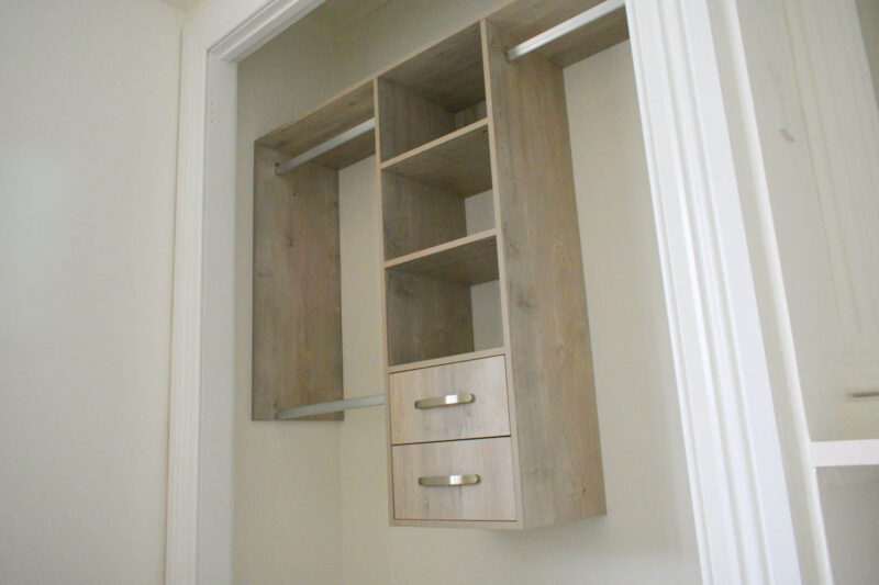 Wooden wardrobe with shelves and drawers inside a closet space.