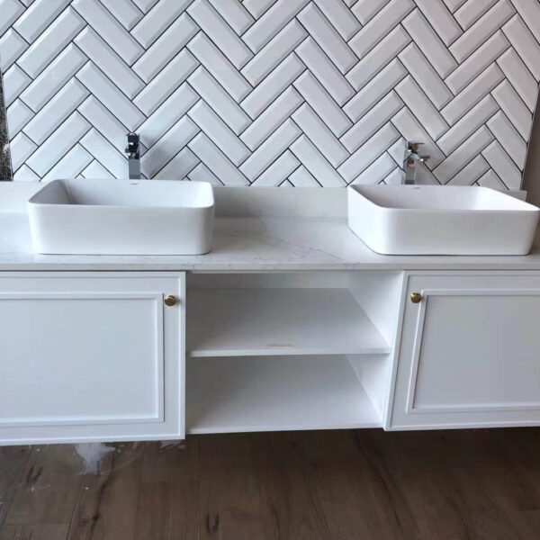 Double sink vanity with herringbone tile backsplash.