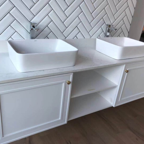 White double sink vanity with herringbone tile backsplash.
