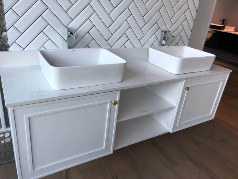 White double sink vanity with herringbone tile backsplash.