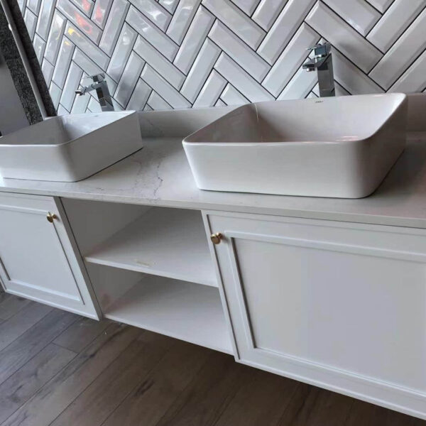 Modern bathroom vanity with two square sinks and herringbone tile backsplash.