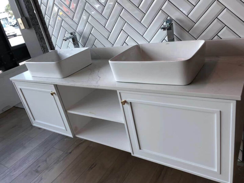 Modern bathroom vanity with two square sinks and herringbone tile backsplash.