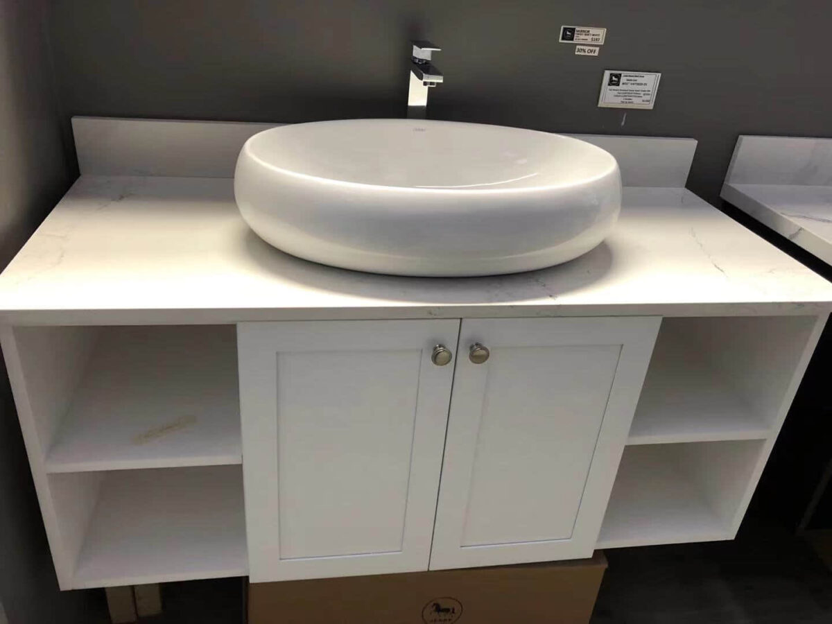 White ceramic bathroom sink on a countertop with storage cabinet.