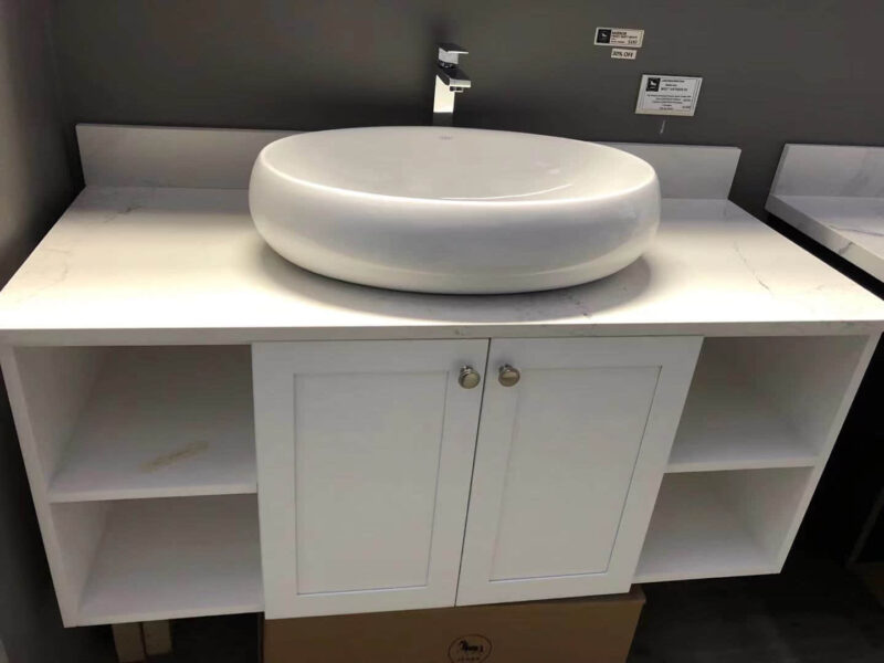 White ceramic bathroom sink on a countertop with storage cabinet.