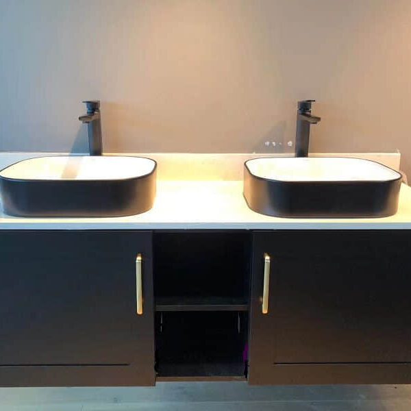 Modern bathroom with double sinks and black cabinetry.