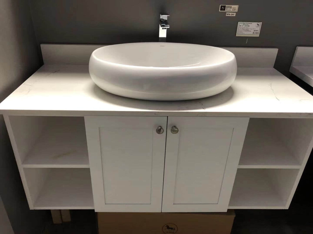 White bathroom vanity with round basin and storage shelves.