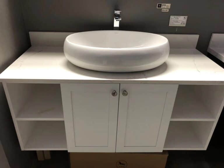 White bathroom vanity with round basin and storage shelves.