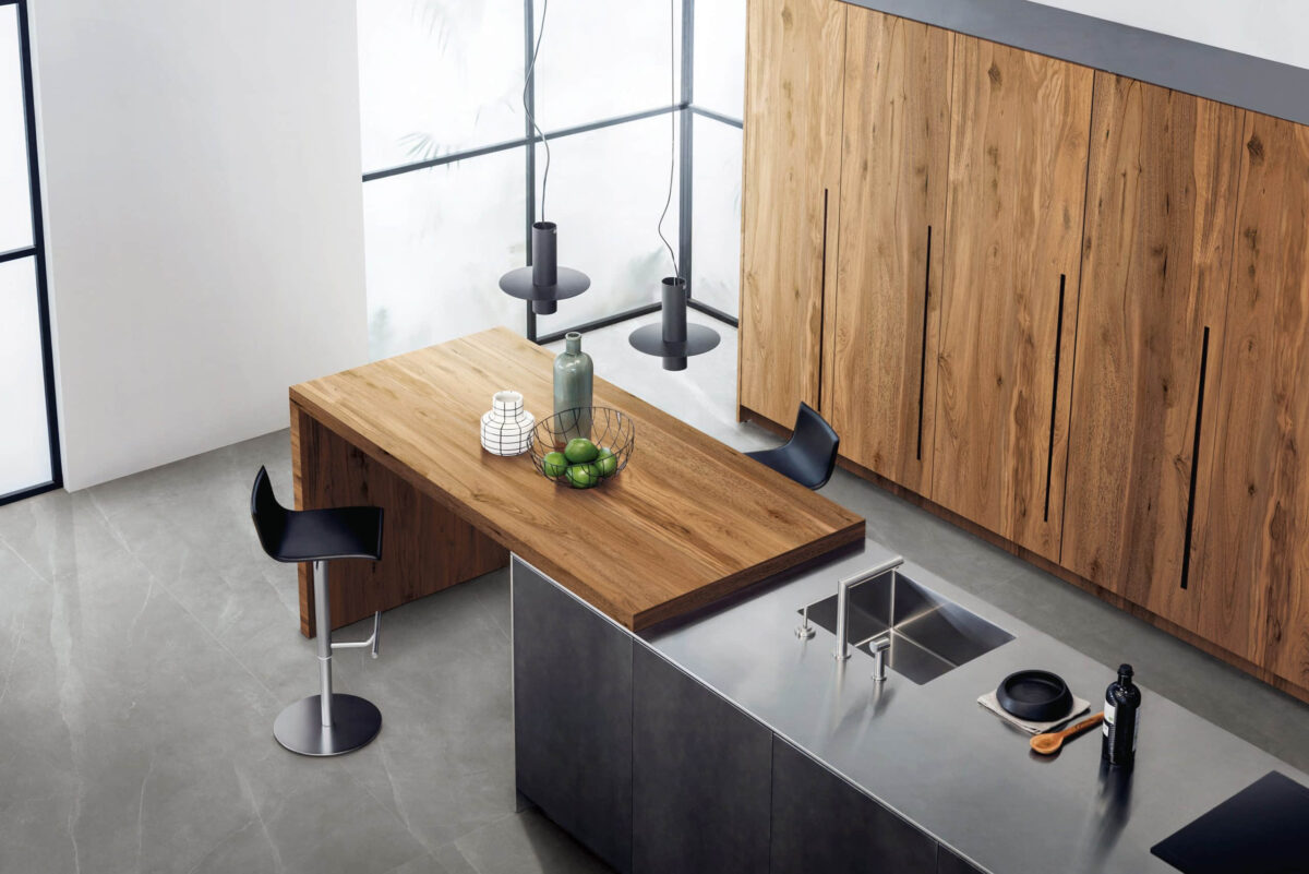 Modern kitchen with wooden table, black stools, and sleek countertops.