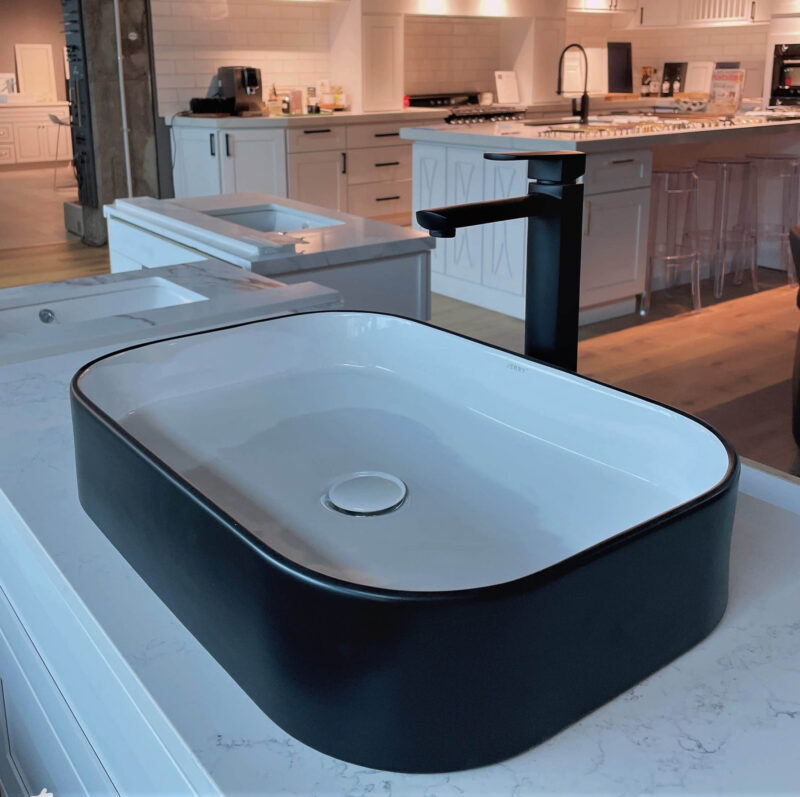 Modern black and white kitchen sink on marble countertop.