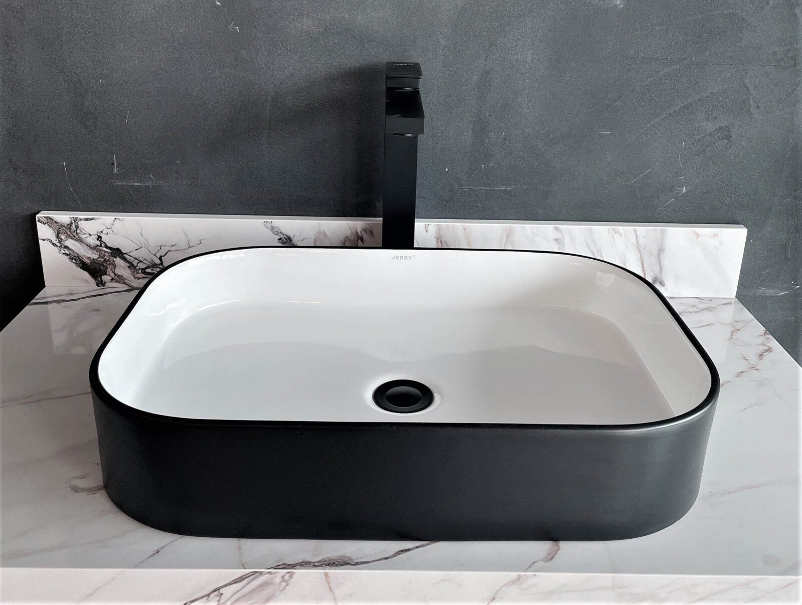 Modern black and white rectangular bathroom sink with marble countertop.