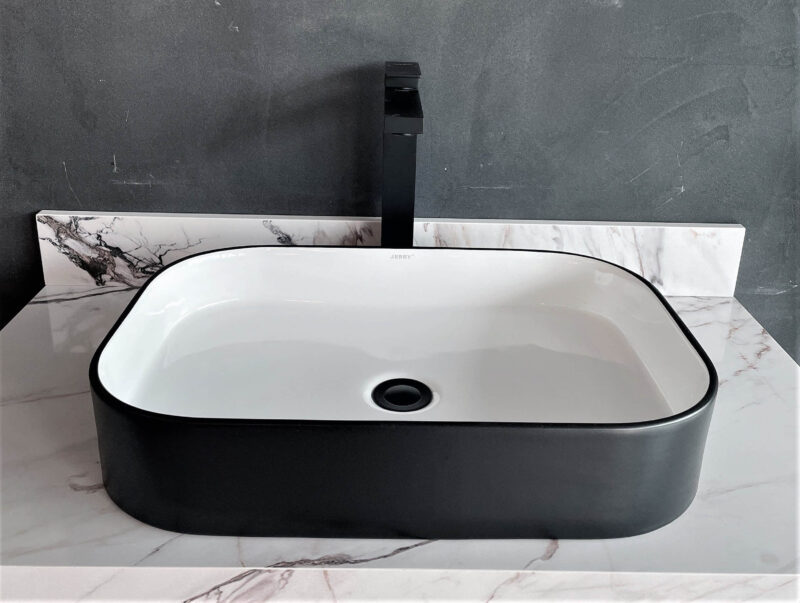 Modern black and white rectangular bathroom sink with marble countertop.
