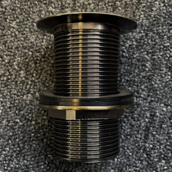 Bronze pop-up waste fitting on textured surface.