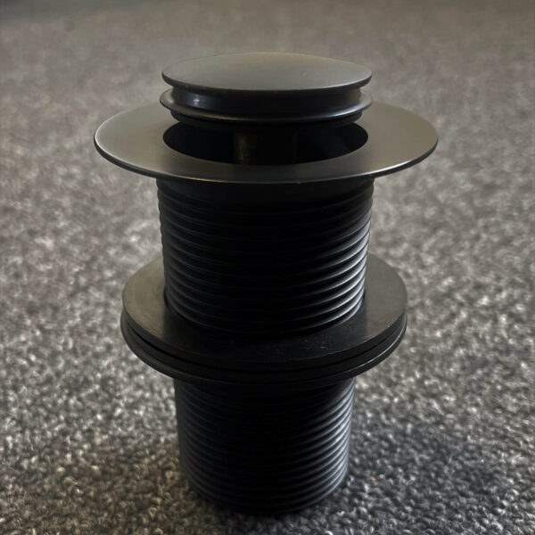 Black 32mm pop-up waste on carpeted floor, top view.