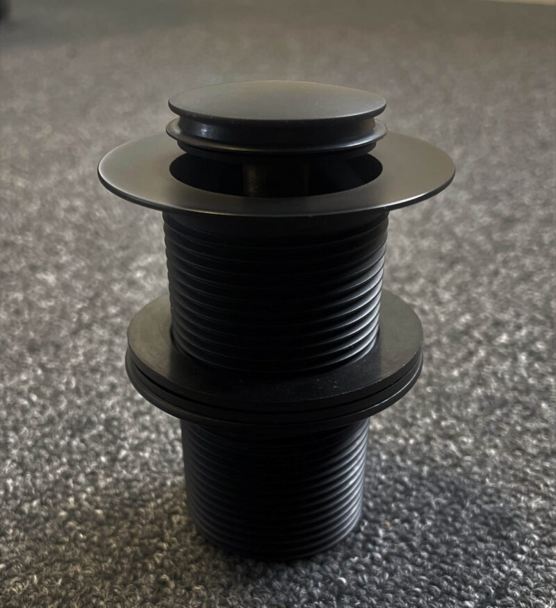 Black 32mm pop-up waste on carpeted floor, top view.